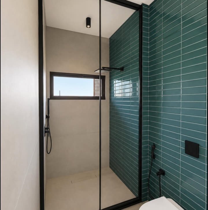 Box de banho em vidro com perfil preto, instalado em banheiro com parede de pastilhas verdes