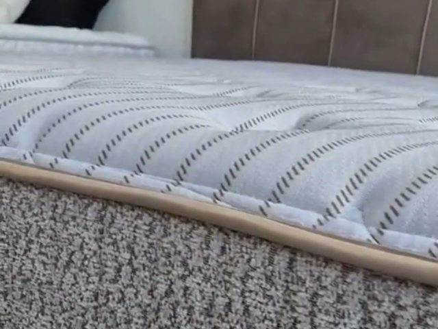 Colchão com pillow top montado sobre base de madeira, com travesseiros na cabeceira