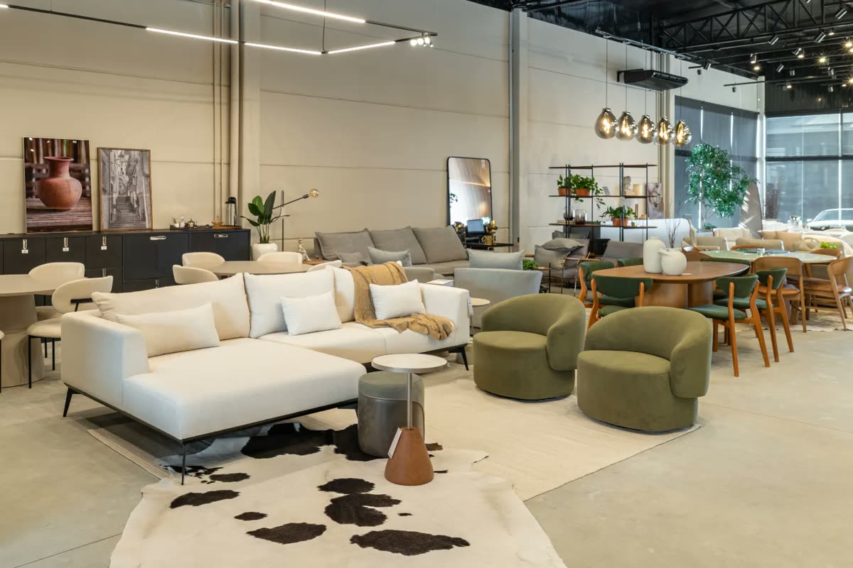 Showroom da Macro Ambientes com ambientes montados: sofá de linho claro, poltronas verdes e mesa de jantar de madeira