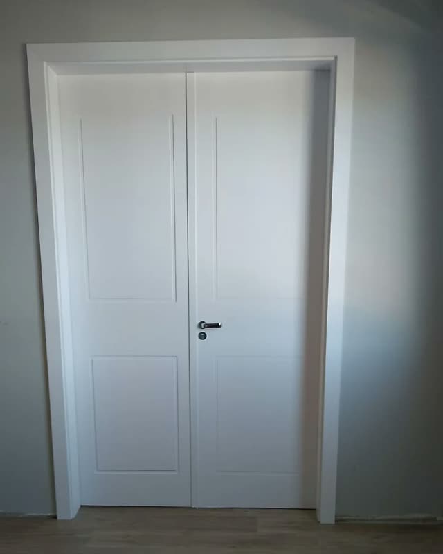 Porta interna branca de duas folhas com almofadas, instalada com batente e guarnição no mesmo tom