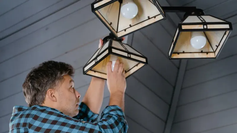 Eletricista instalando uma luminária de teto em uma residência