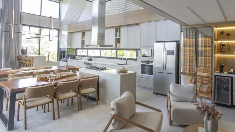 Cozinha e sala de jantar integradas, com ilha e armários planejados de pé-direito duplo